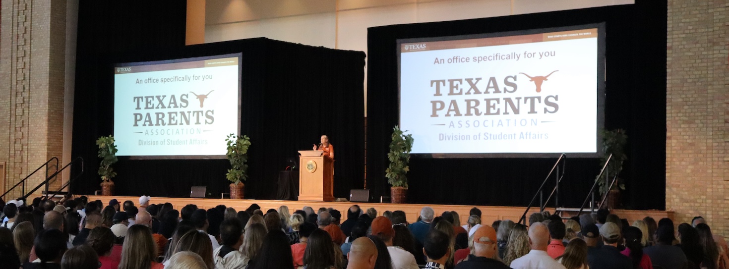 Texas Parents Director Susie Smith on stage with Texas Parents logo displayed on video screens during UT's Family Orientation