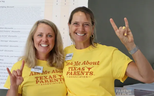 Two Texas Parents Association volunteers smiling and holding hookem hand signs during UT’s Family Orientation