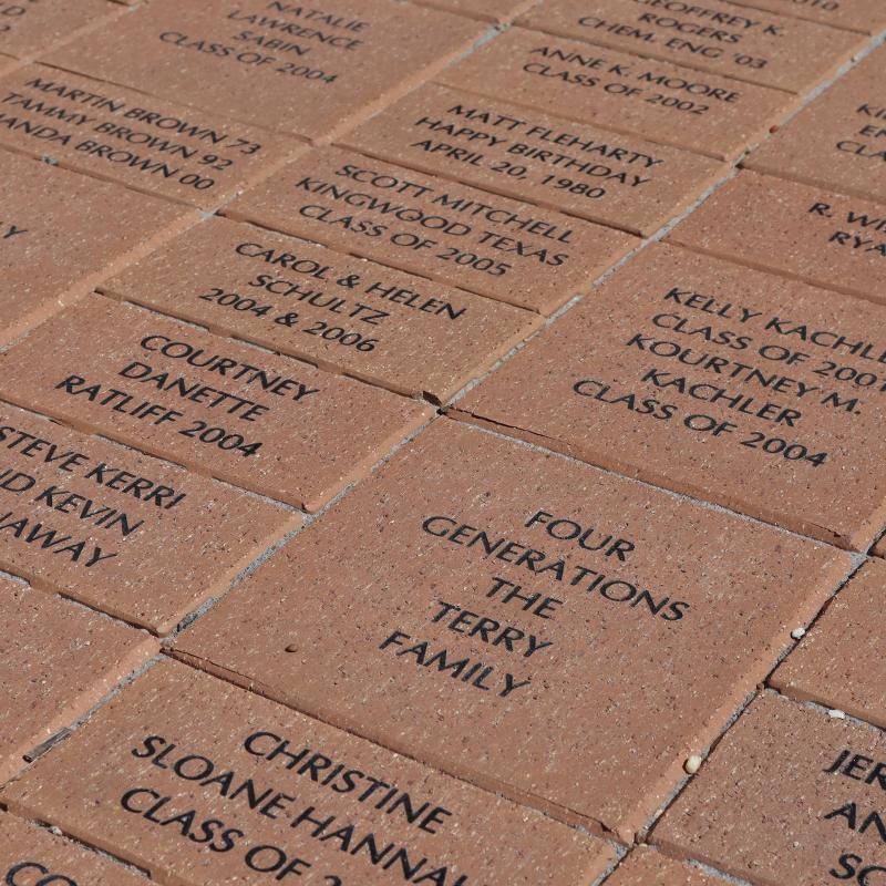 Detail of brick pavers etched with student and family names in front of UT’s Student Services Building